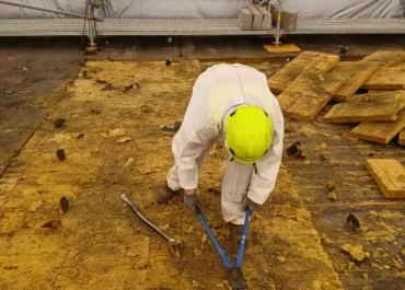 Demontáž střešní konstrukce s azbestem ve kontrolovaném pásmu na Letišti Praha – pracovník v ochranném oděvu při odstraňování materiálu